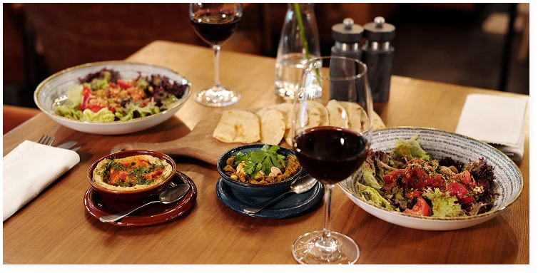 A table laid with Mediterranean dishes and glasses of red wine