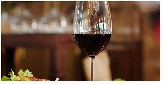 A close-up of a glass of red wine on a restaurant table with appetisers and dishes